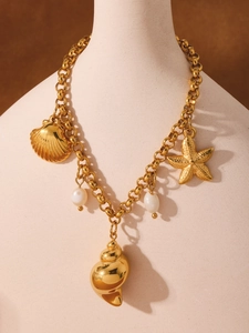 Dettaglio della collana a catena dorata con ciondoli a forma di conchiglia e stella
