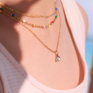 Three-layer gold necklace with colorful beads and rainbow pendant worn by a model