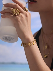 Detail eines vergoldeten Armbands mit Herzanhängern und einem sonnenförmigen Ring