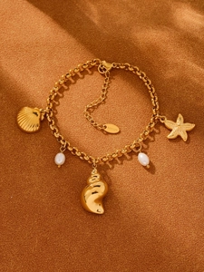 Dettaglio di ciondoli a stella marina dorata, conchiglie e perle su un bracciale