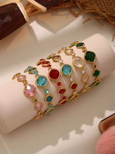 Detalle de cinco pulseras de piedras de cristal coloridas en un soporte de joyería dorado