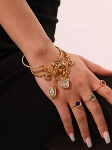Detail of gold-plated geometric bracelet with white crystals and colorful stone rings