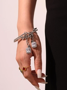 Close-up of a silver chain bracelet with zircon pendants and layered gemstone rings