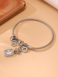 Detailed close-up of silver rope chain bracelet with rectangle crystal and zircon charms