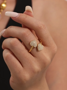 Dettaglio di un anello a doppio cuore in oro con pavé di zirconi bianchi lucidi