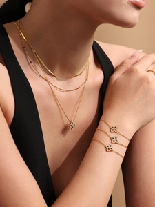 Detailansicht der goldfarbenen Kleeblatt-Halsketten und Armbänder mit Zirkonia-Besatz