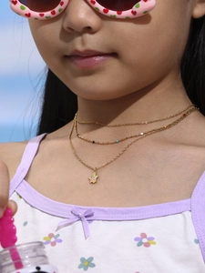 Detailed view of kids' layered gold star necklace with colorful beads on a model