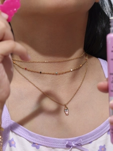 Dettaglio della collana dorata con ciondoli a forma di gelato e perline colorate