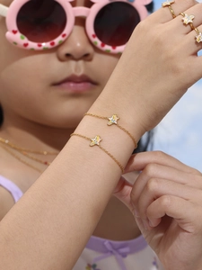 Detail of colorful unicorn charms on gold bracelets and rings worn by a child model