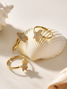 Close-up of three colorful unicorn enamel rings on a shell for girls jewelry