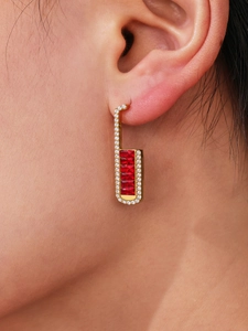 Close-up of gold rectangular earrings with five red zircons and sparkling micro-pave diamonds