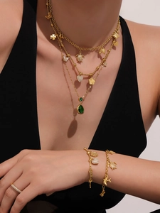 Detail van de gouden gelaagde ketting met vlinderhangers en groene edelsteen