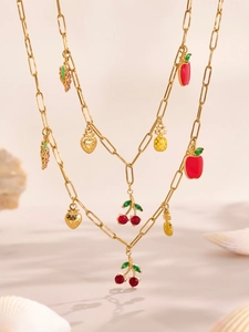 Detalle de dijes de frutas doradas con cereza y piña en una cadena de eslabones