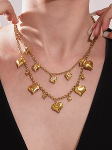 Detail of double-layer gold necklace with heart charms and lettered rhinestone accents
