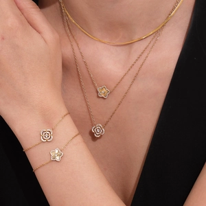 Parure de bijoux dorés avec pendentifs trèfle et zircons portés par un mannequin