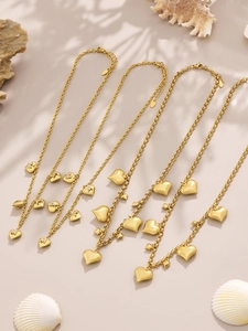 Detail of 18k gold plated heart necklaces with zircon letters on a summer beach setup
