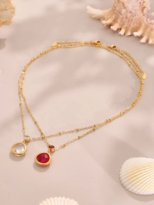 Detail van 18k vergulde kettingen met peervormige robijn en kristallen hangers