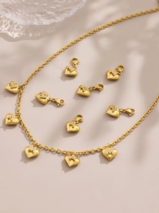 Close-up of gold plated heart pendants with zircon letter M and A inlay jewelry detail