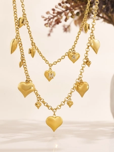 Detailed view of layered gold necklace with M and A heart pendants and sparkling crystals