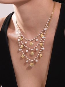 Detail of layered gold shell and pearl beaded necklace with sparkling zircons on model