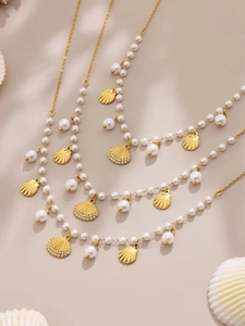 Detail of tiered gold necklaces with pearls and crystal shell charms in beach style