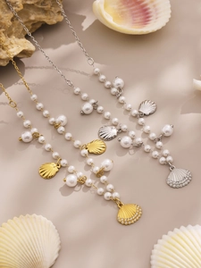 Detail of shell pearl necklaces with gold plating and cubic zirconia on warm sand background