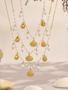 Detail of layered gold shell necklace with faux pearls and sparkling zircon accents
