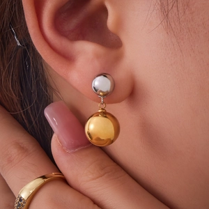 Minimalist two-tone round ball earrings in gold and silver finish on female model