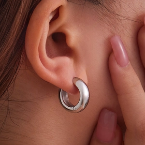 Polished silver stainless steel chunky hoop earring shown on a model's ear