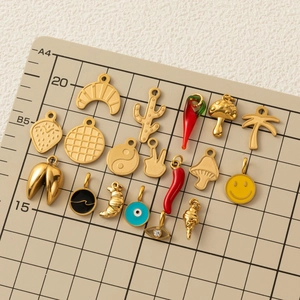 Vari ciondoli placcati in oro 18K con motivi alimentari e moda su tappetino da taglio