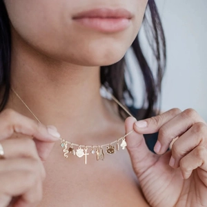 18K gold plated titanium necklace with cross, mushroom and shell charms on a female model