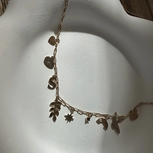 Detail view of 18K gold plated charms including heart and star on a white ceramic tray
