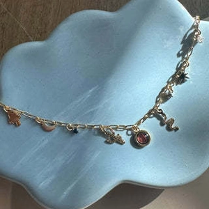 Detail view of 18K gold plated chain with bohemian charms on a blue display plate