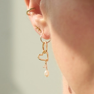 Detailed view of gold earring set with heart links, cubic zirconia, and freshwater pearl