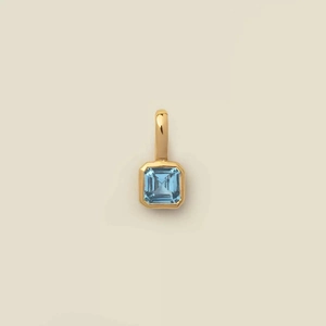 Gros plan du pendentif plaqué or 18K avec pierre précieuse bleu clair taille émeraude