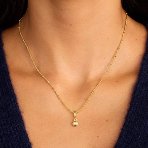 Detail van gouden satellietketting met 3D-honkbal hanger gedragen door een vrouwelijk model