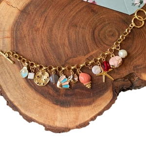 Golden ocean theme charm bracelet with colorful shells and starfish on wood