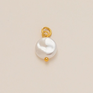 Colgante de perla con aro dorado y detalle de cuenta sobre un fondo beige elegante