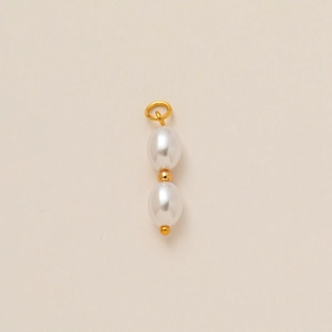Primer plano del colgante de doble perla con detalles dorados y diseño lineal vertical