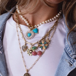 Layered gold chain and pearl necklace featuring colorful fruit pendants and heart charms