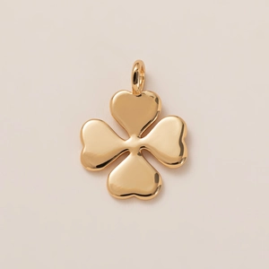 Polished 18K gold four-leaf clover pendant with heart-shaped leaves on a smooth surface