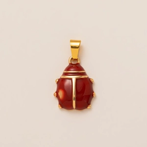Macro detail of red enamel ladybug pendant with 18K gold plated metal finish