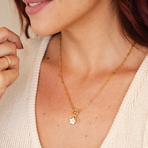 Detail of 18k gold plated necklace with flower charm and angel number tag on a model