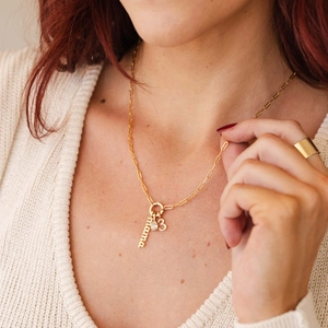 Close-up of gold paperclip chain necklace with mama, number 3, and zircon charms