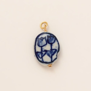 Detalle de colgante de cerámica artesanal con estampado de tulipán azul y aro dorado