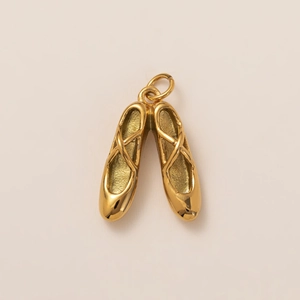 Detailed view of 18K gold plated ballet pointe shoe charms with intricate cross-strap textures