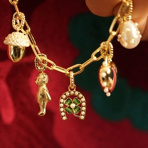 Golden link bracelet with charms like a green clover, red heart, and bear on festive background