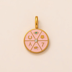 Détail macro du pendentif porte-bonheur doré 18K avec émail rose et pierre bleue centrale