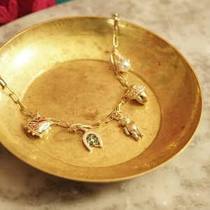 Golden multi-charm bracelet with heart and horseshoe pendants on an elegant tray