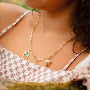 Detail of vintage gold necklace with baroque pearls and clover horseshoe charms on a model